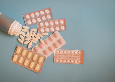 Bottle with pills and blisters with pills and capsules on blue background. Top view, copy space.