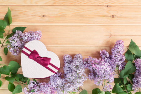 Heart shape gift box and lilac flowers on wooden background. Copy space for your text.の写真素材