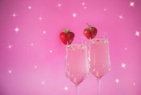 Two glasses of champagne and fresh strawberry on pink background. Selective focus.の写真素材