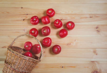 Ripe tomatoes in wicker basket on wooden background. Top view, copy space.の写真素材