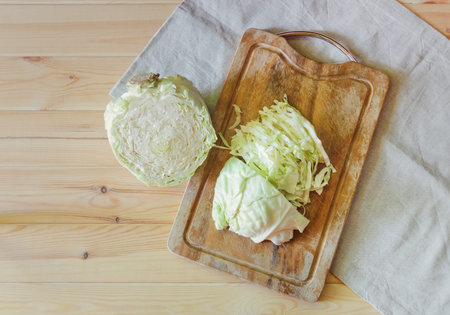 Fresh raw cutted cabbage on cutting board on wooden background. Top view, copy space.