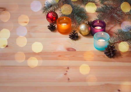 Fir branches, candles in colorful glass candlesticks, pine cones and christmas balls.  View with copy space.の写真素材