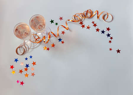 Two glasses of champagne and colorful bright confetti in shape of stars on blue background. Top view, copy space.の写真素材