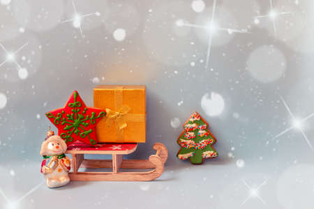 Gold gift box,  gingerbread cookies, wooden sledge and christmas decoration snowman on blue background. Holiday mood. View with copy space.の写真素材