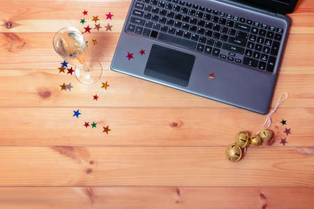 Christmas workspace with laptop, glass of champagne  and jingle bells. Top view, copy space.の写真素材