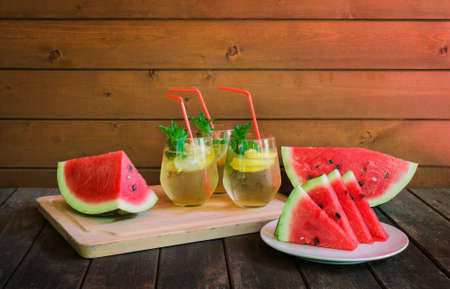 Pieces of watermelon,  slices of watermelon and glasses of refreshing summer lemonade on rustic wooden table. Selective focus. View with copy space.の写真素材