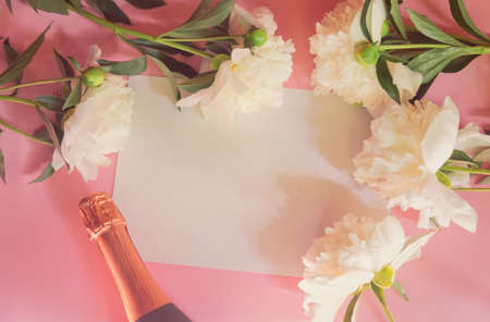 Empty card for your notes, bottle of rose champagne and white peonies on pink background. Top view, copy space.の写真素材