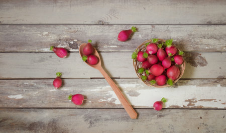 Fresh garden radish in wooden spoon and in wicker basket on aged wooden table. Top  view.