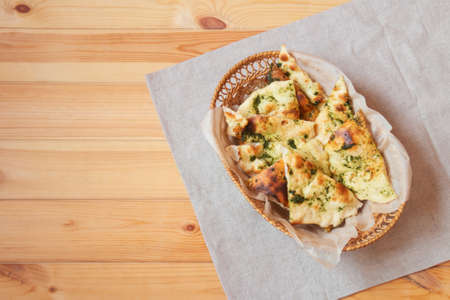Wheat focaccia bread with aromatic pesto sauce in wicker basket on wooden table. Top view with copy space.の写真素材