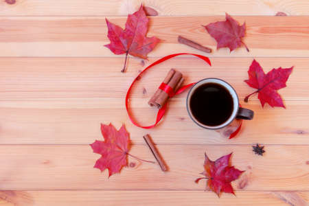 Mug of coffee, autumn leaves and cinnamon sticks on wooden table. Top view, copy space.の写真素材