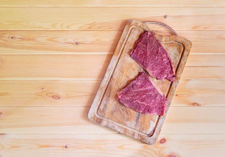 Raw fresh marbled meat Black Angus Steaks on cutting board on wooden table. Top view, copy space.の写真素材