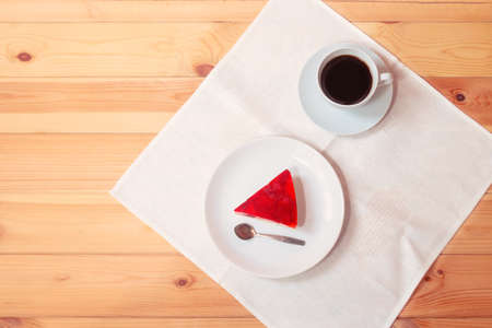 Piece of strawberry cake and cup of coffee on wooden table.の写真素材