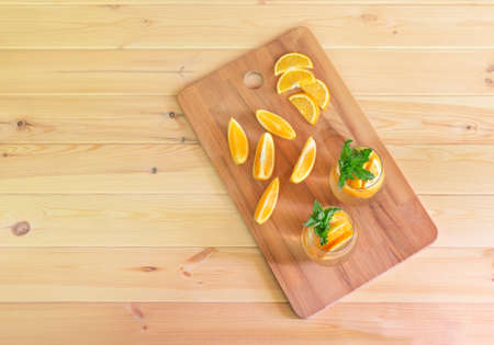 Cold summer orange lemonade in glasses and fresh oranges near on wooden table. Top view with copy space.の写真素材