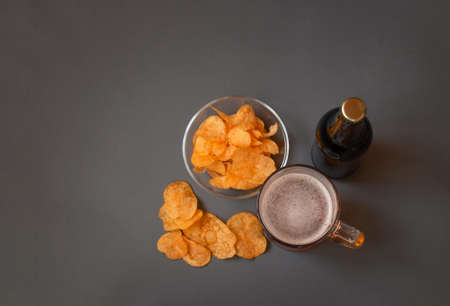 Mug of beer, bottle of beer and potato chips on gray background. Selective focus. Top view with copy space.の写真素材