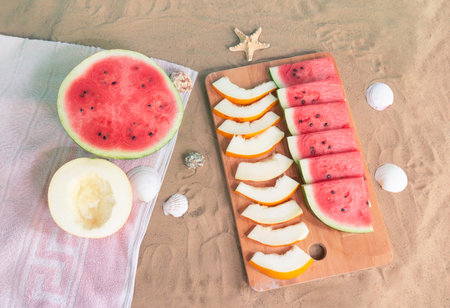 Half of watermelon and melon, cutting board with slices of watermelon and melon, starfishes and...
