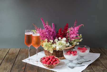 Beautiful astilbe and hydrangea flowers, glasses of rose champagne, homemade italian dessert panna cotta and fresh raspberry on wooden table. Selective focus. View with copy space.の写真素材