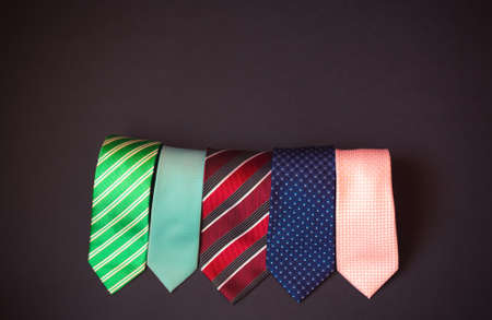 Rolled stylish multi colored neckties on dark background. Top view, copy space.の写真素材