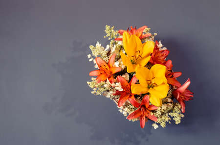 Beautiful bouquet of orange and yellow lilies and white hydrangea flowers on gray background. Top view, copy space.の写真素材