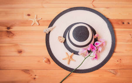 White summer hat  and purple orchid on wooden background. Starfishes and seashells near. Beach holidays concept. Top view, copy space.の写真素材