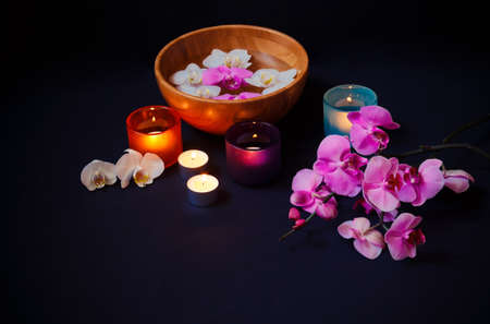 Colorful orchids and burning candles in  colorful candlesticks on dark background. View with copy space.の写真素材