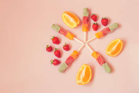 Spiral orange-strawberry ice cream and fresh fruits on pink background. Top view. Copy space.の写真素材
