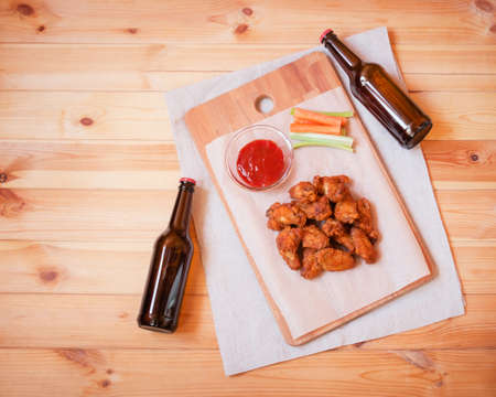 Roasted chicken wings and bottles of beer on wooden table. Top view, copy space.の写真素材