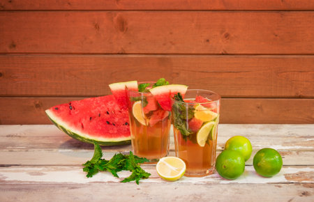 Watermelon mojito cocktail on aged wooden table. Watermelon, limes and mint near. Selective focus....