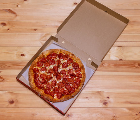 Freshly baked pepperoni pizza in box on wooden  table. Top view.の写真素材
