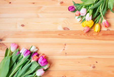 Colorful spring tulip flowers as border on wooden background. Top view, copy space.