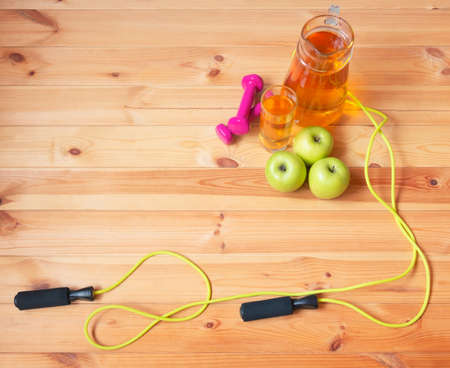 Pitcher and glass of apple juice, dumbbells, jumping rope and fresh apples near. Top view with copy space.の写真素材