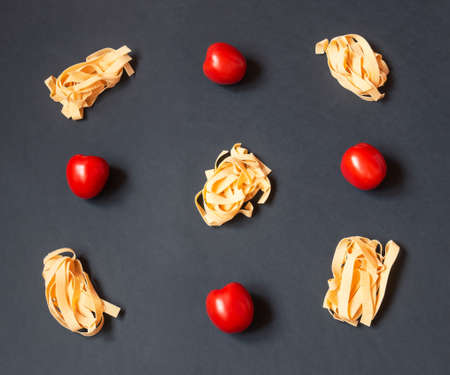 Food pattern made of pappardelle pasta and fresh  tomatoes on dark background. Top view.の写真素材