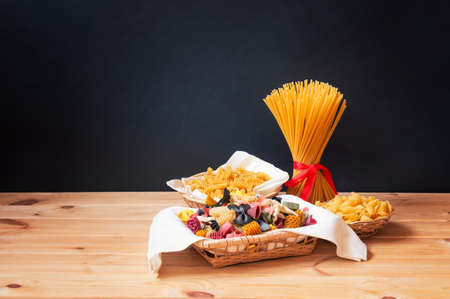 Different kinds of raw pasta on  wooden table. View with copy space.の写真素材