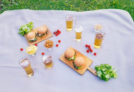 Picnic with beer mugs and glasses, homemade burgers and beer snacks. top view.