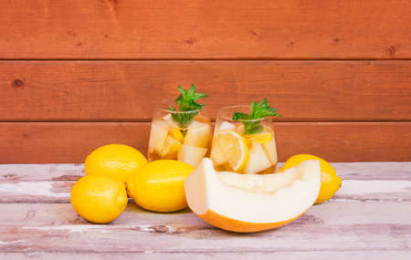 Two glasses of refreshing summer melon lemonade, lemons and melon on aged wooden table. view with copy space.の写真素材
