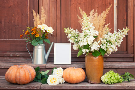 Frame, bouquet of white roses, helenium and dry grass, bouquet of hydrangea and dry grass, pumpkins and white roses on steps of rustic wooden ladder. view with copy space.の写真素材