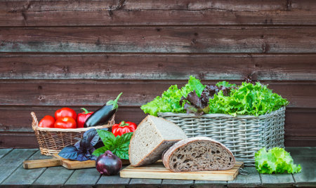 Bread, fresh vegetables, colorful salad and basil leaves on rustic wooden table. view with copy space.の写真素材