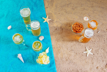 Cold beer, beer snacks, starfishes and seashells on towels on sand beach. Top view, copy space.の写真素材