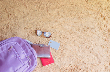 Backpack, passport, wallet, credit card and sunglasses on sand beach. Beach holiday concept. Top view, copy space.の写真素材