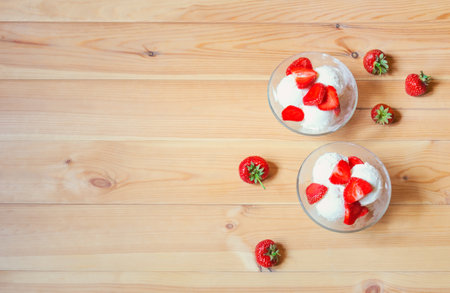 Sundae ice cream with strawberry slices on wooden table. Top view, copy space.の写真素材