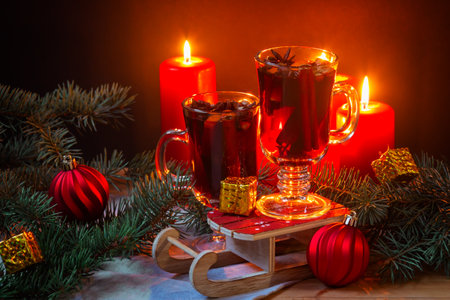 Glasses of mulled wine, burning candles, Christmas balls, pine branches and gifts on wooden table. Selective focus. Christmas concept.の写真素材