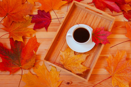 Cup of coffee and colorful autumn maple leaves on wooden table. Top view.の写真素材
