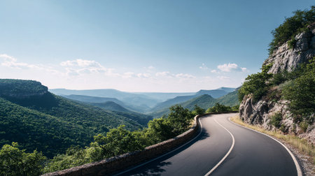 Scenic Asphalt Road Winding Through Lush Green Mountains on a Sunny Dayの素材