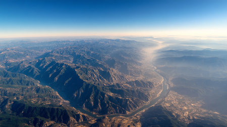 Aerial view of a winding river through a mountainous landscape under clear sky.の素材