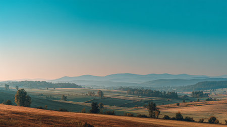 Serene Countryside at Dawn: Golden Fields and Distant Hills Panoramaの素材
