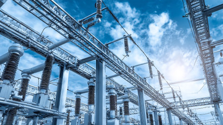 high voltage electric substation with blue sky and sun in the backgroundの素材