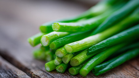 Fresh and vibrant green spring onions resting on rustic wooden surfaceの素材