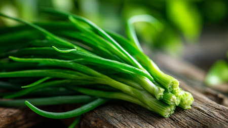 Vibrant green spring onions bundled on weathered wood surface, ready for cookingの素材