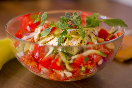 Salad of tomato, pepper, cucumber and purple onion, in olive oil, with menta and oregano sprig.の写真素材