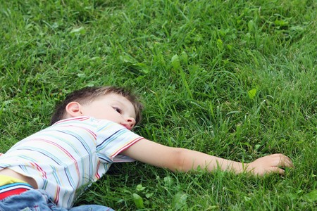 Tired boy relaxing in the grass, after the big runningの写真素材