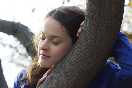 women in the autumn forest, dreaming next to a treeの写真素材